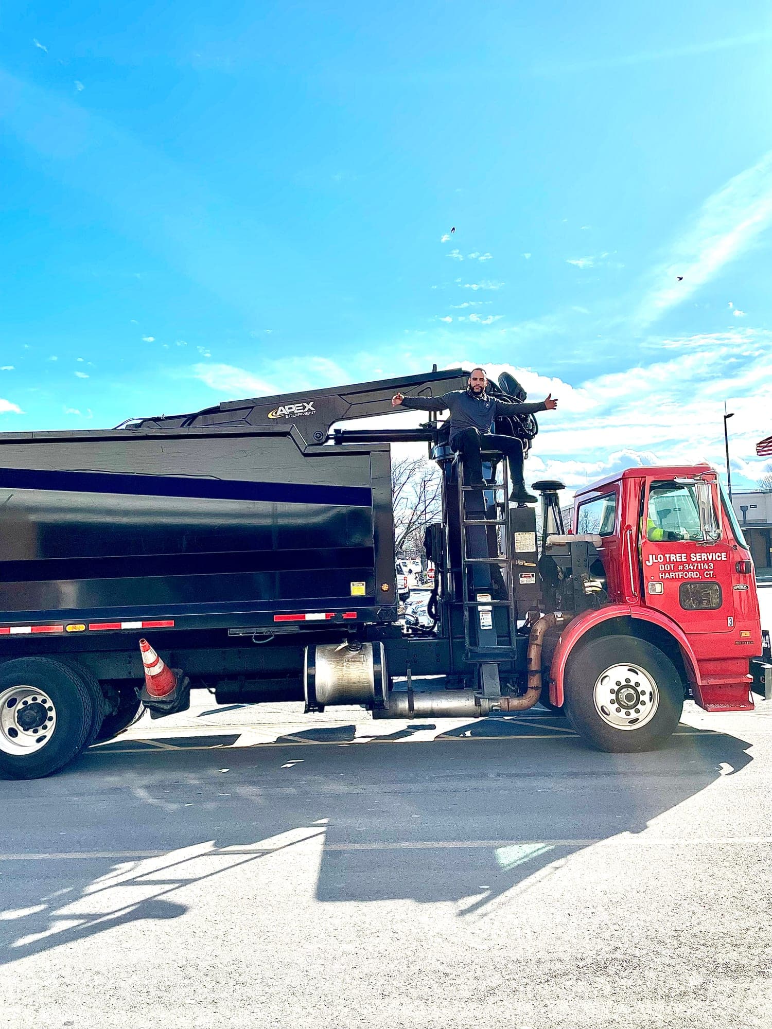Red and black JLO grapple truck parked in the sun