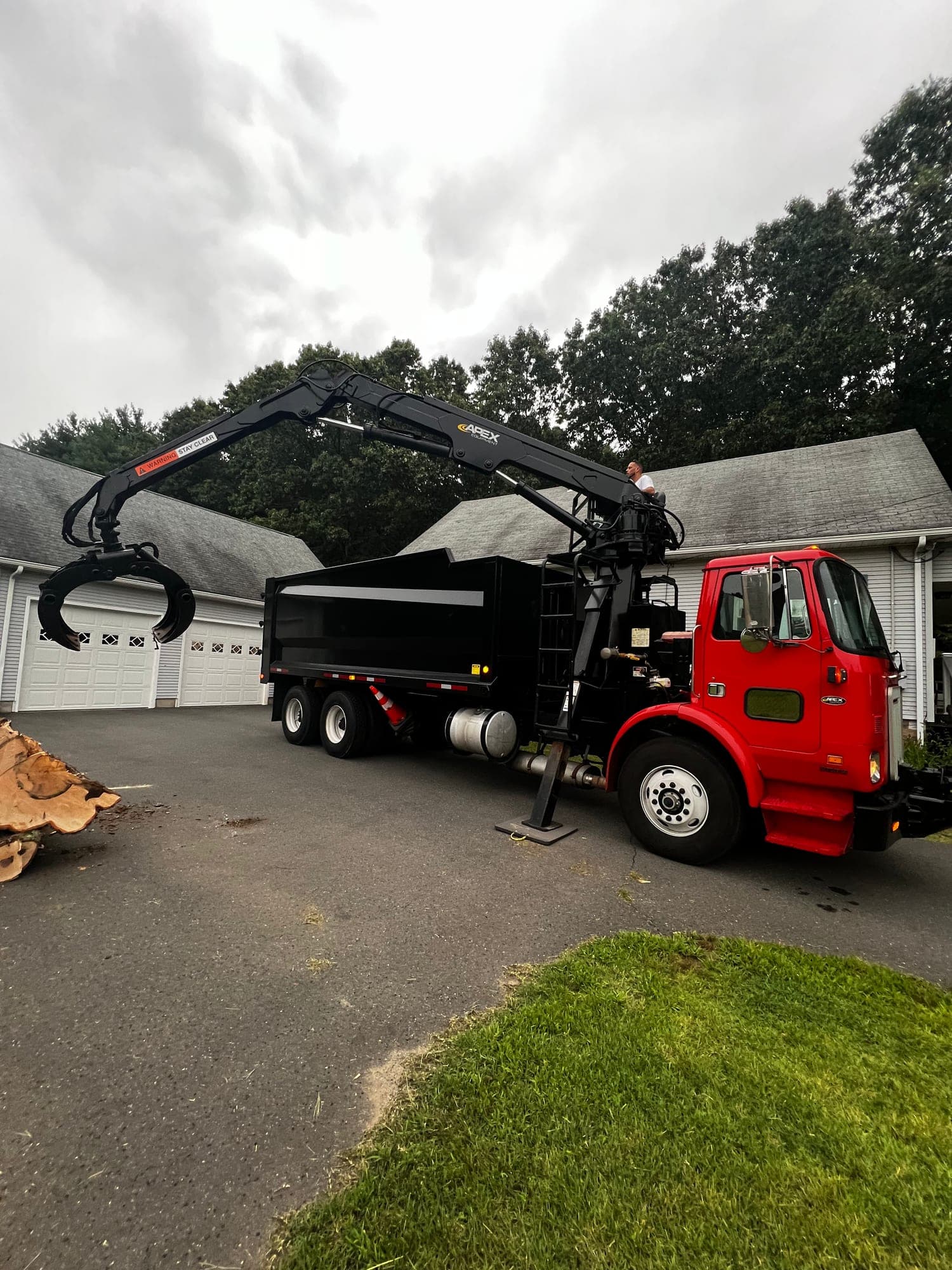 Red grapple truck with loaded dump body in a driveway