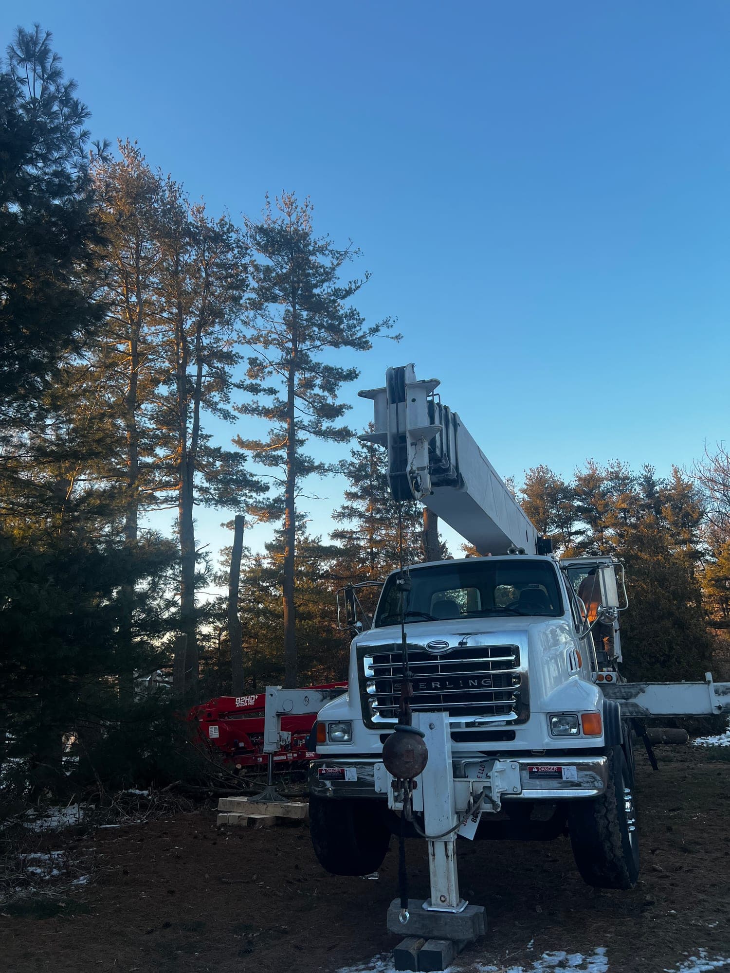 Crane truck with outriggers set in a wooded lot