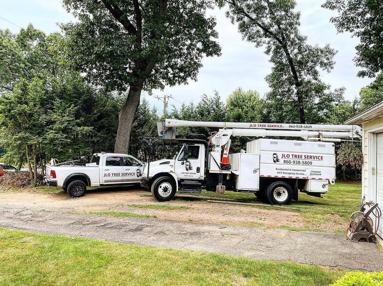 JLO Tree Service bucket truck and pickup parked on a lawn