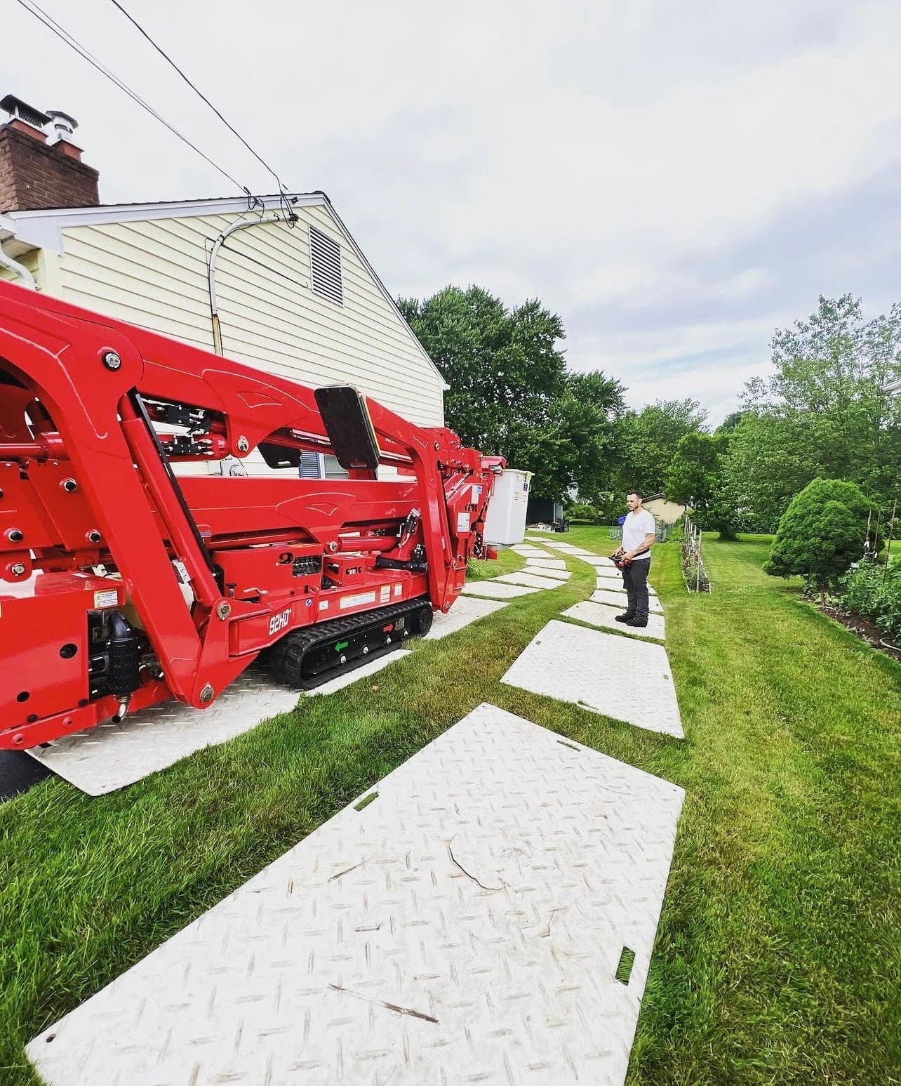 Red spider lift driving across ground-protection mats laid over a lawn