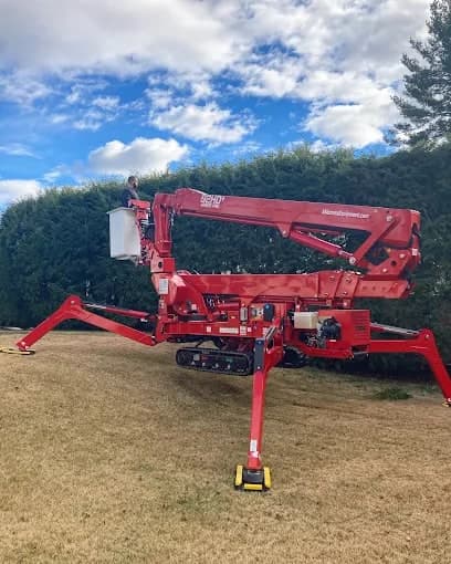 Red spider lift parked on a lawn under a blue sky