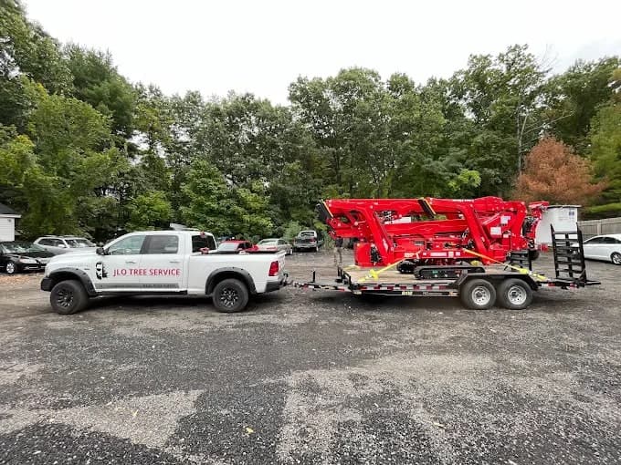 JLO pickup towing a red spider lift on a trailer