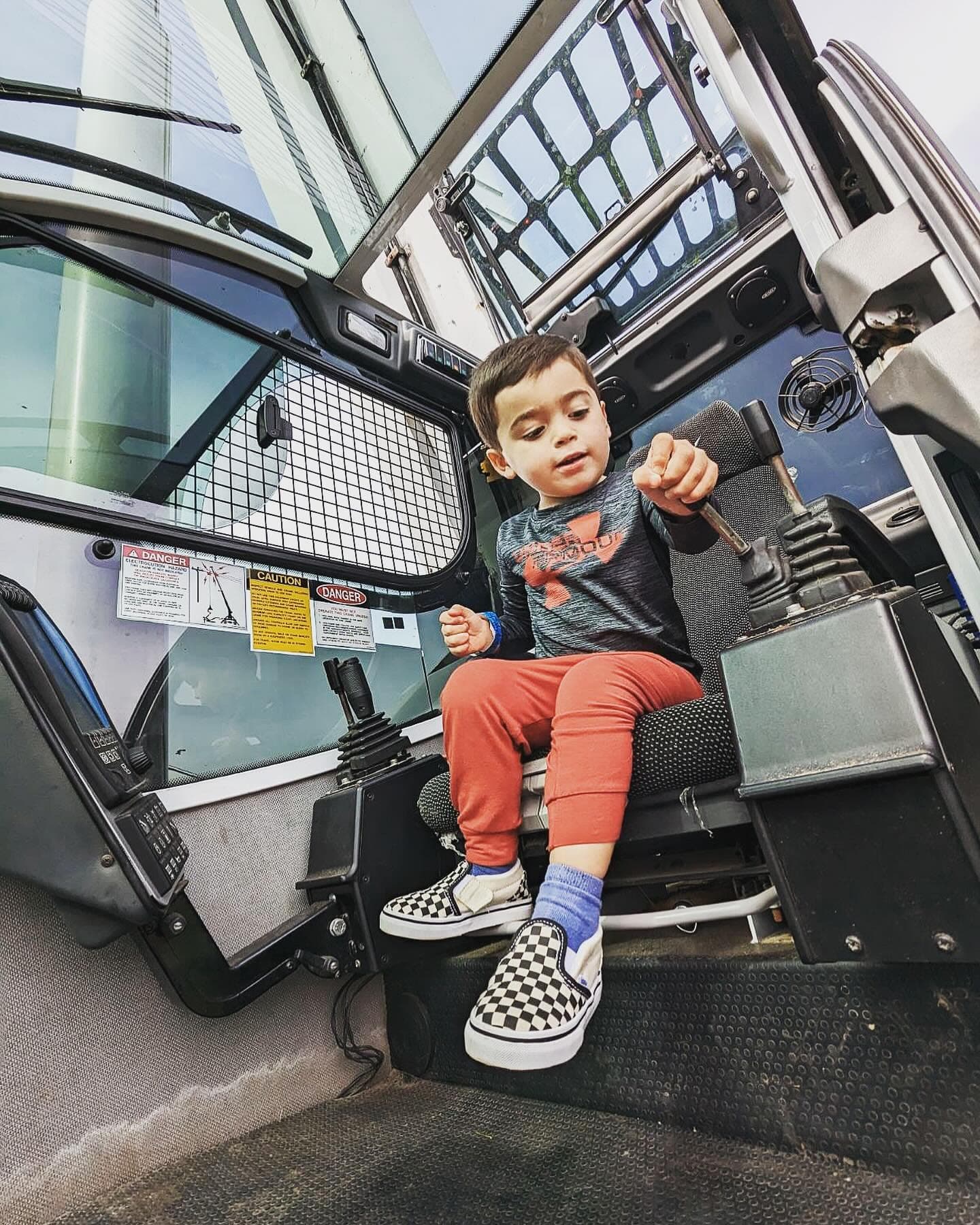 Young child sitting in the operator seat of a JLO Tree Service machine
