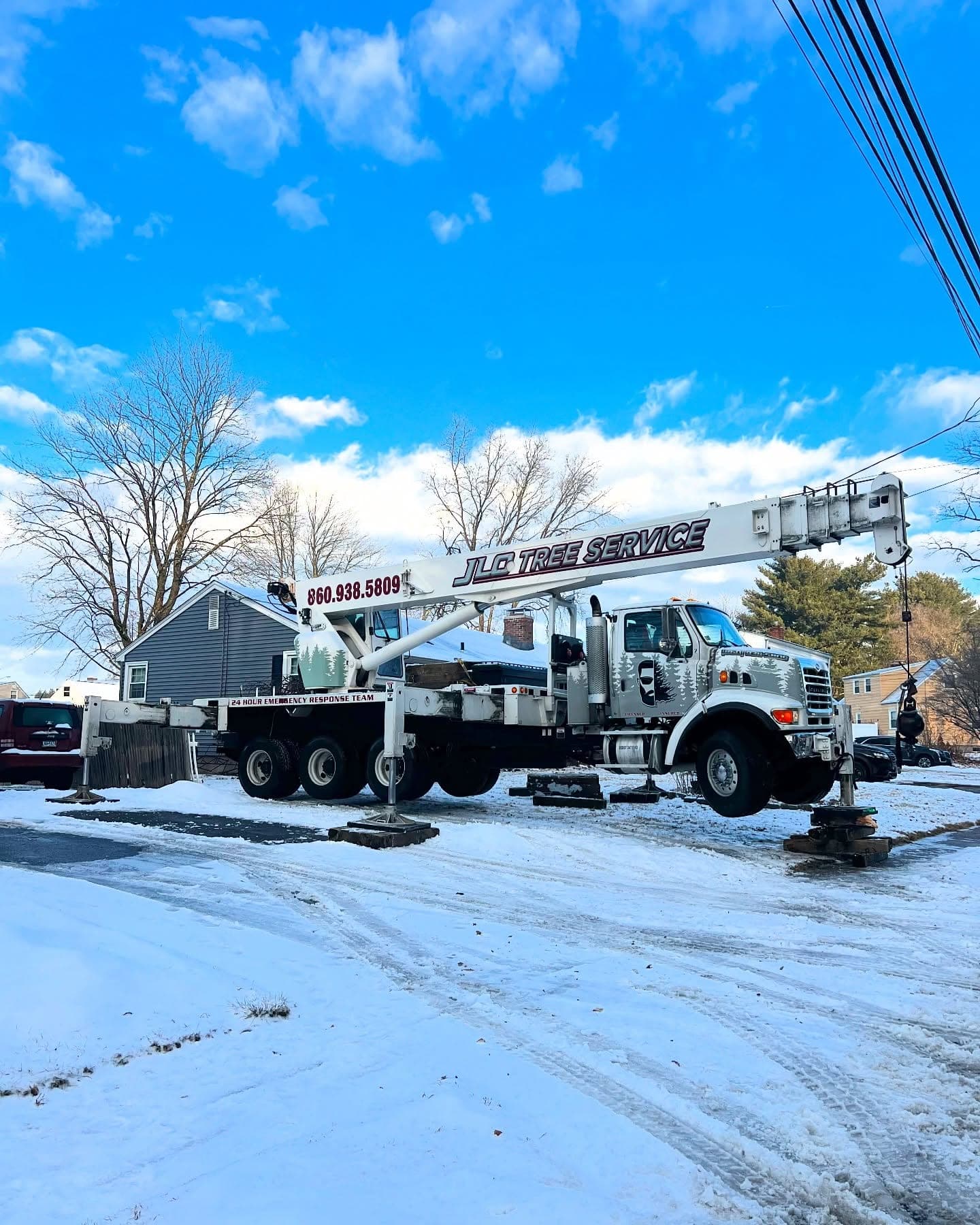 JLO Tree Service crane truck set up on a snowy street
