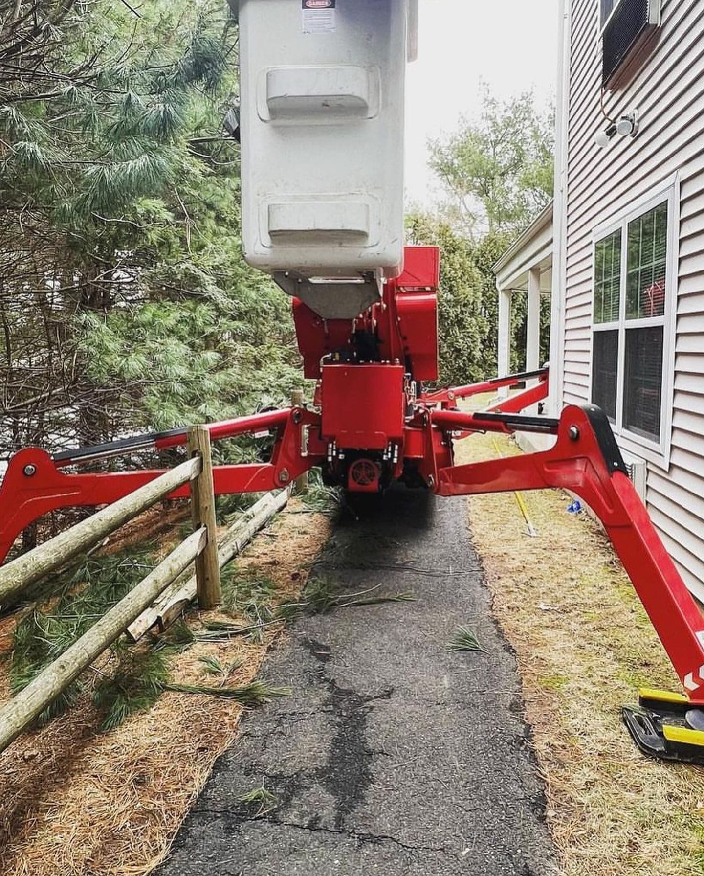 Spider lift driving through a narrow side yard along a fence