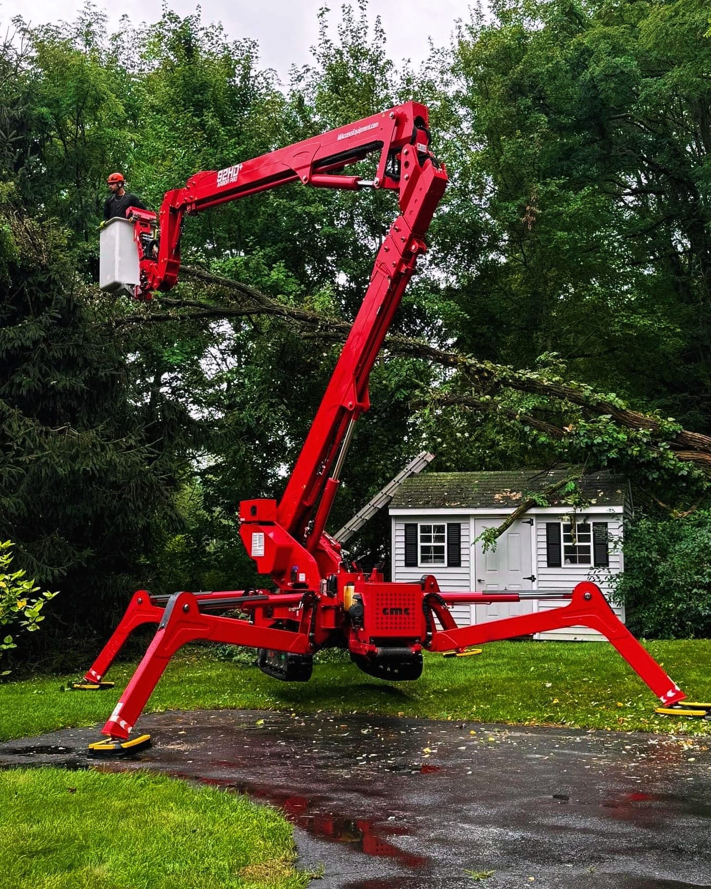 JLO's red spider lift with its boom raised into the trees
